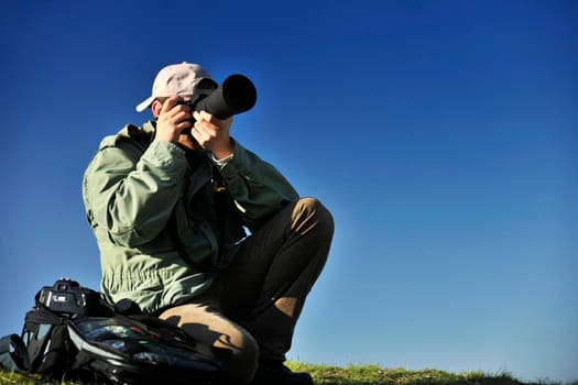 Nature photographer with digital camera on top of the mountain