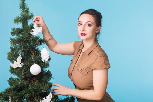 People and holidays concept - Portrait of smiling young woman with Christmas tree on blue background