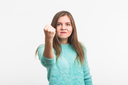 furious young brunette woman shows fist. The girl is very angry and ready to use his fists. Negative aggressive emotions on her face