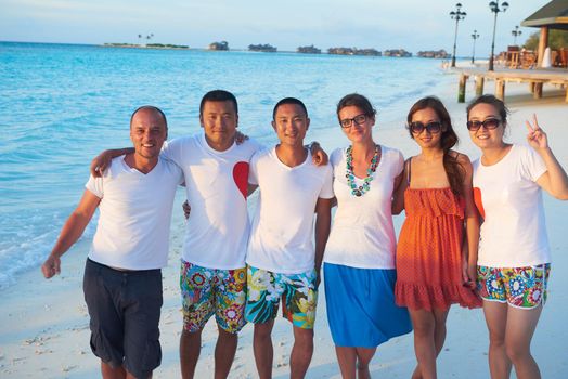 group of friends on beautiful beach at sunset going back to home