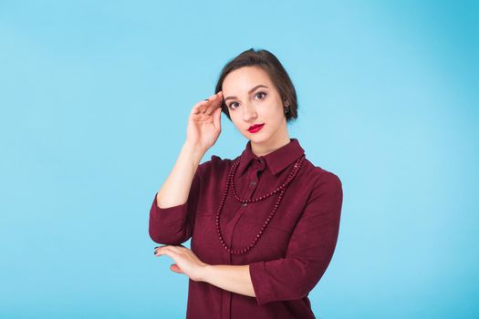 Portrait of young beautiful ginger woman with freckles cheerfuly smiling looking at camera. Isolated on pastel blue background. Copy space.