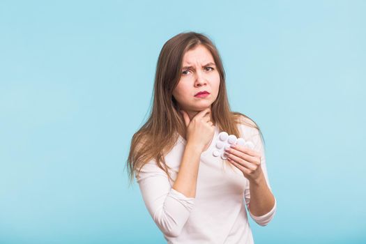 Sore throat. Woman touching the neck on blue background.