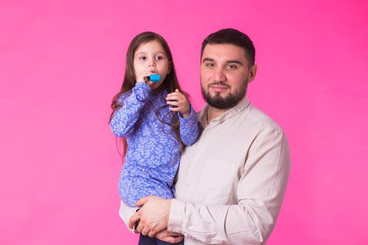 Happy father holding baby daughter in hands over pink background.