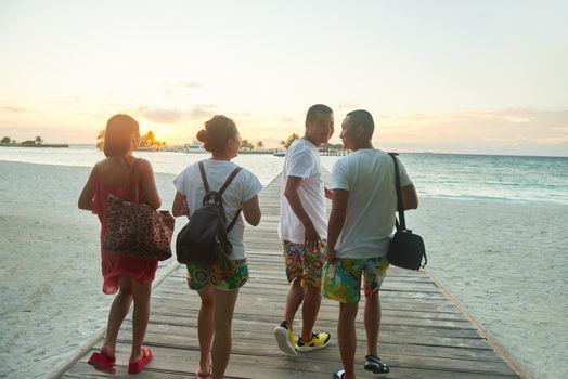 group of friends on beautiful beach at sunset going back to home