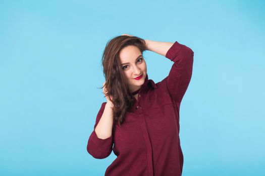 Portrait of young beautiful ginger woman with freckles cheerfuly smiling looking at camera. Isolated on pastel blue background. Copy space.