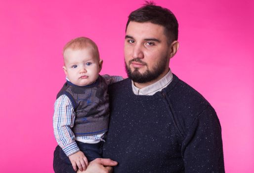 happy father with a baby son isolated on a pink background.