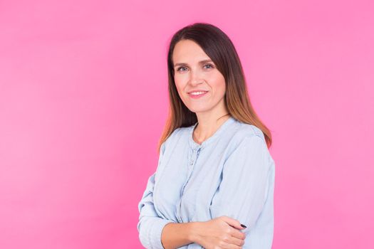 Smiling Woman in shirt posing in studio on pink background.