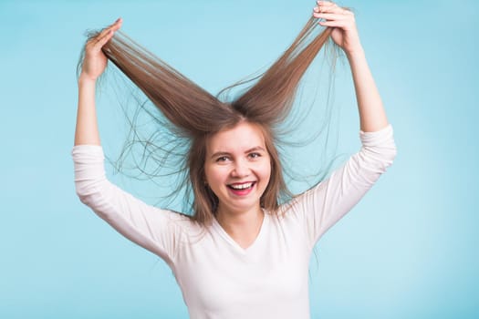 Attractive woman holding to the hair. so happy and funny girl. isolated blue background,