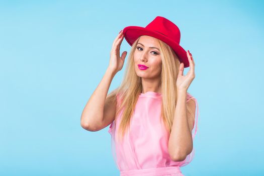 beauty fashion summer portrait of blonde woman with red lips and pink dress on blue background with copy space.