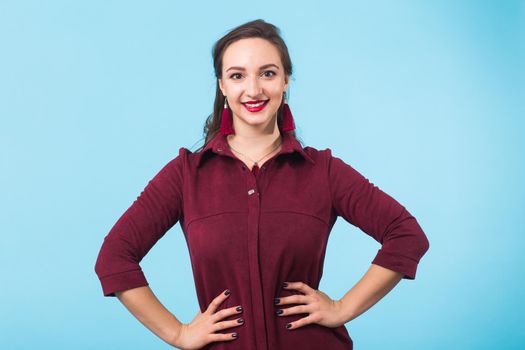 Portrait of young beautiful ginger woman with freckles cheerfuly smiling looking at camera. Isolated on pastel blue background. Copy space.