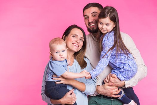 Happy family portrait smiling on pink background.