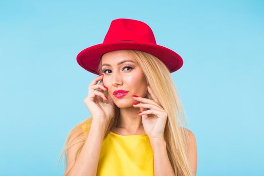 Portrait of smiling blonde woman in fashionable look on blue background. Style, fashion, summer and people concept.