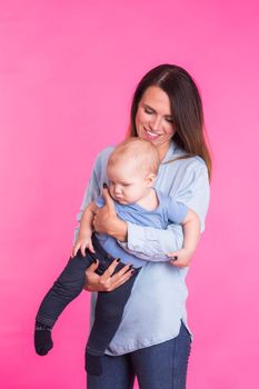 happy young mother with a baby child on pink background.