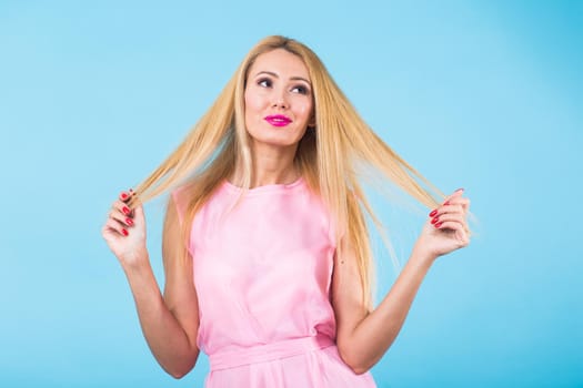 Portrait of happy cheerful smiling young beautiful blond woman on blue background.