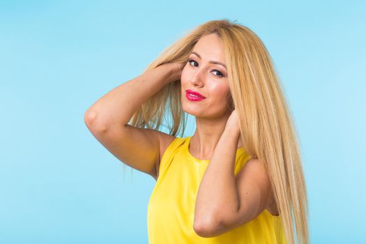 Portrait of smiling blonde woman in fashionable look on blue background. Style, fashion, summer and people concept.