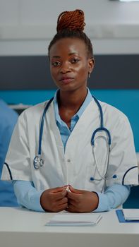 Black medic on video call online conference sitting at desk in medical cabinet. African american doctor using remote communication method on internet for telemedicine treating people