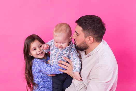 Father with children having fun on pink background.