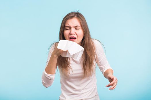 Young woman has a runny nose on blue background.