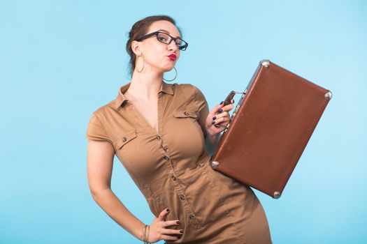 Beautiful woman with old retro suitcase on blue background.