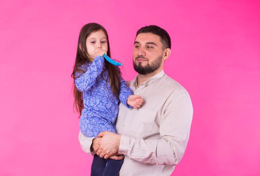 Happy father with his baby daughter on pink background.