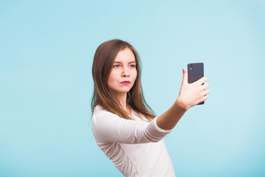 Beautiful girl taking selfie over blue background.