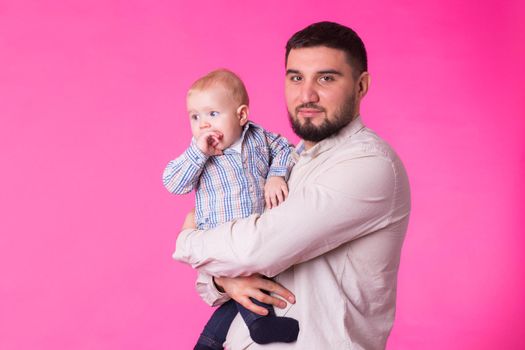 Baby in the daddy hands. Pink background