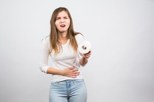 Sick woman with hands pressing her crotch lower abdomen, holding paper roll. Medical problems, incontinence, health care concept.