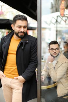 Fosus on sitting man ner fashionable guy standing at street cafe outdoor. Concept of life style and male fashion.