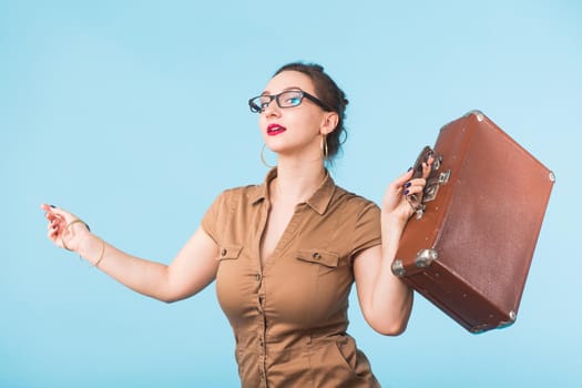 Portrait of excited young woman holding a suitcase isolated over blue background, Travel, holidays and vacation concept