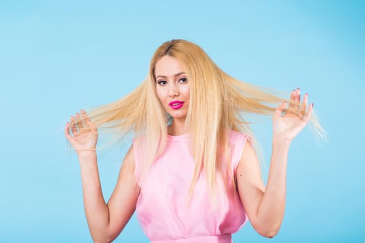 Portrait of happy cheerful smiling young beautiful blond woman on blue background.