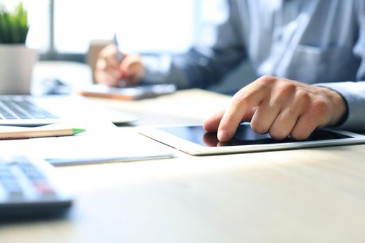 Young modern business man working using digital tablet while sitting in the office