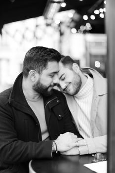 Black and white photo of two caucasianyoung gays sitting and hugging, holding hands. Concept of same sex couple and lgbt.