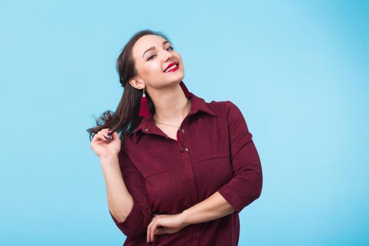 Portrait of young beautiful ginger woman with freckles cheerfuly smiling looking at camera. Isolated on pastel blue background. Copy space.