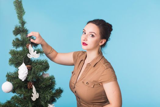 People and holidays concept - Portrait of smiling young woman with Christmas tree on blue background