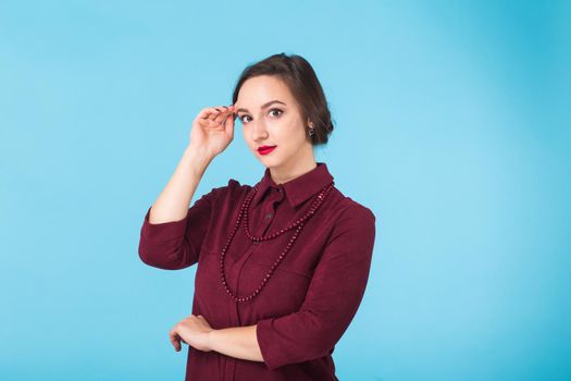 Portrait of young beautiful ginger woman with freckles cheerfuly smiling looking at camera. Isolated on pastel blue background. Copy space.