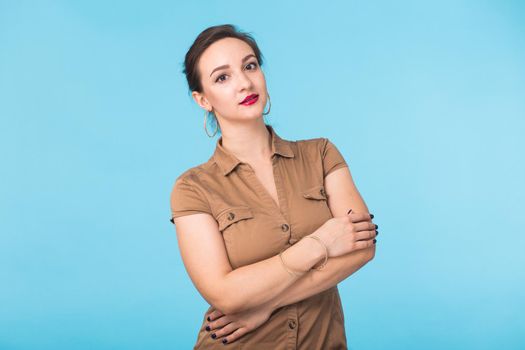 Portrait of young beautiful ginger woman with freckles cheerfuly smiling looking at camera. Isolated on pastel blue background. Copy space.