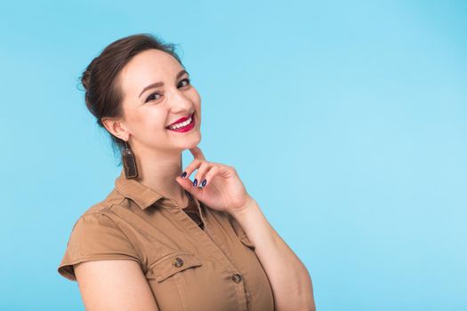 Portrait of young beautiful ginger woman with freckles cheerfuly smiling looking at camera. Isolated on pastel blue background. Copy space.