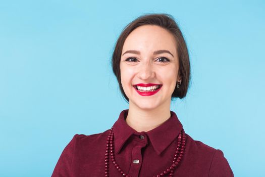 Portrait of young beautiful ginger woman with freckles cheerfuly smiling looking at camera. Isolated on pastel blue background. Copy space.