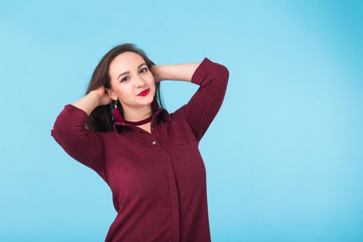 Portrait of young beautiful ginger woman with freckles cheerfuly smiling looking at camera. Isolated on pastel blue background. Copy space.