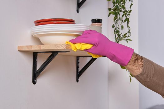 Close up Image of strong hands in pink gloves. They tries to clean the shelf above the cooking surface. Different detergents used