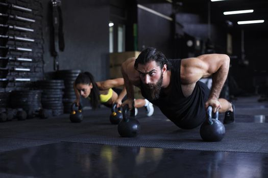 Sporty man and woman doing push-up in a gym