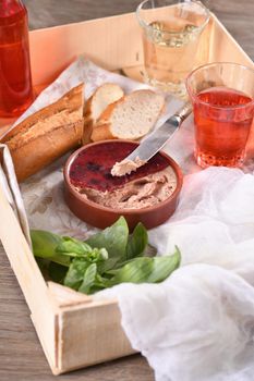 Delicate chicken pate with pureed cranberries, drenched in jelly. Served with pieces of baguette and fruit drink, in a wooden box. Country style food. 