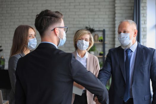 Business people in medical masks shaking hands, finishing up a meeting
