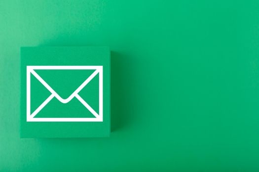 Email concept. Envelope drawn on toy square against dark green background with copy space. Concept of marketing, newsletter, promotion information and virtual communication concept.