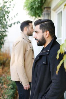 Focus on fisrt caucasian brunette man standing near boy and house. Concept of male person and two brothers.