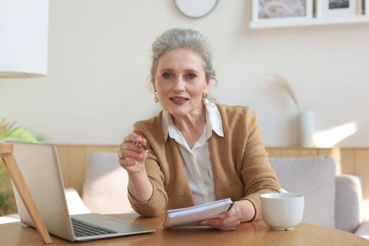 Portait of smiling beautiful middle aged woman looking at camera, making video call, job interview or online dating