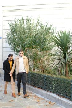 Caucasian handsome gays walking and holding hands in city. Concept of same sex couple and lgbt.