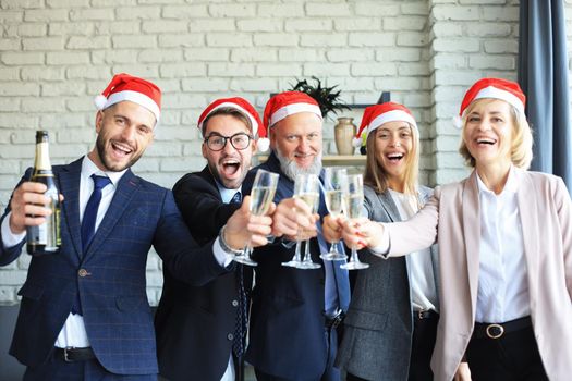 Office business coworkers celebrating winter holidays together at work and drinking champagne in office. Merry Christmas and Happy New Year