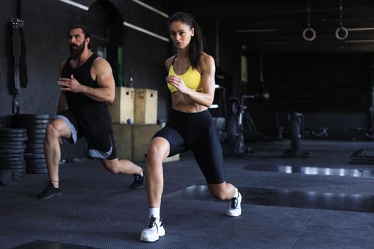 Fitness couple in sportswear doing squat exercises at gym