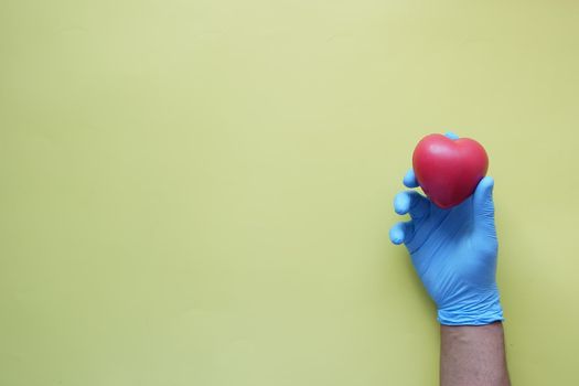 man hand in protective gloves holding red heart .